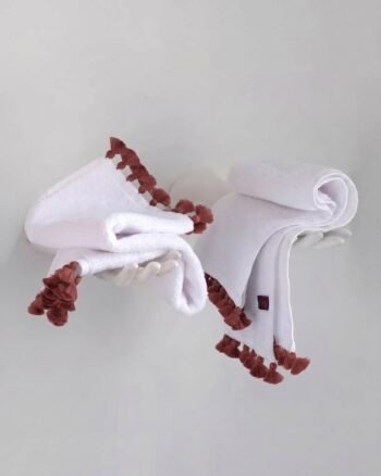 Petite serviette invité LAMU blanche en éponge de coton de prestige ornée de pompons délicats signée V.Barkowski