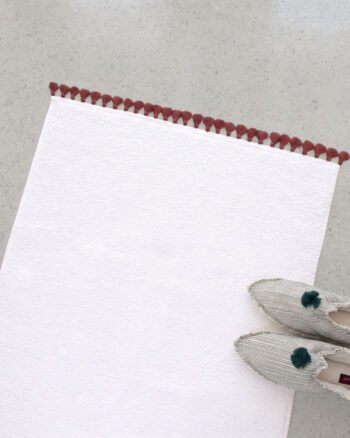Luxury LAMU bath mat in heavy and absorbent white cotton with handmade artisanal tassel details.